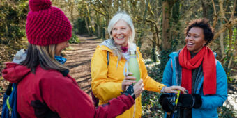 Three women on a hike stop for a hot and cold drinks break