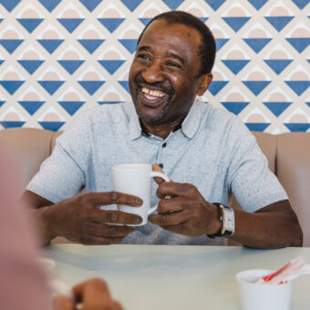 A happy middle-aged man holding a cup of tea in a cafe
